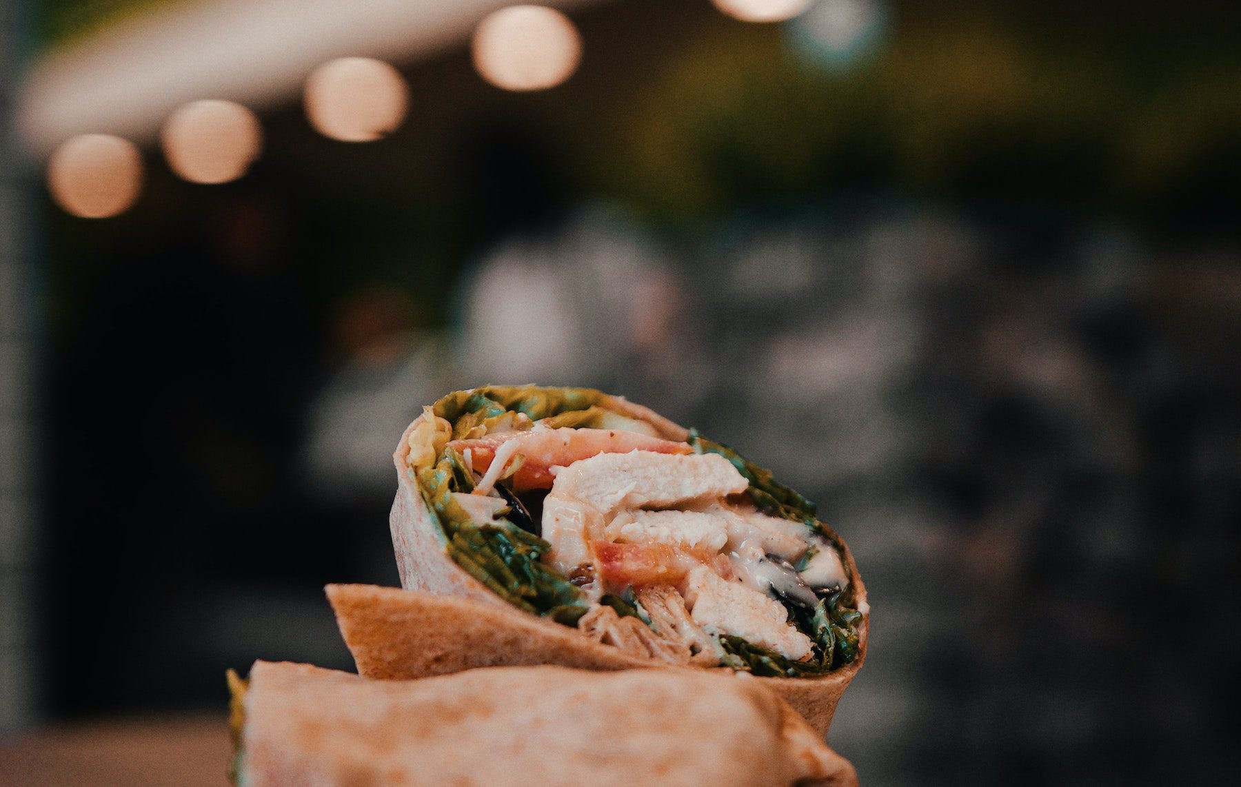 A burrito cut in half and stacked with a blurred bokeh background.