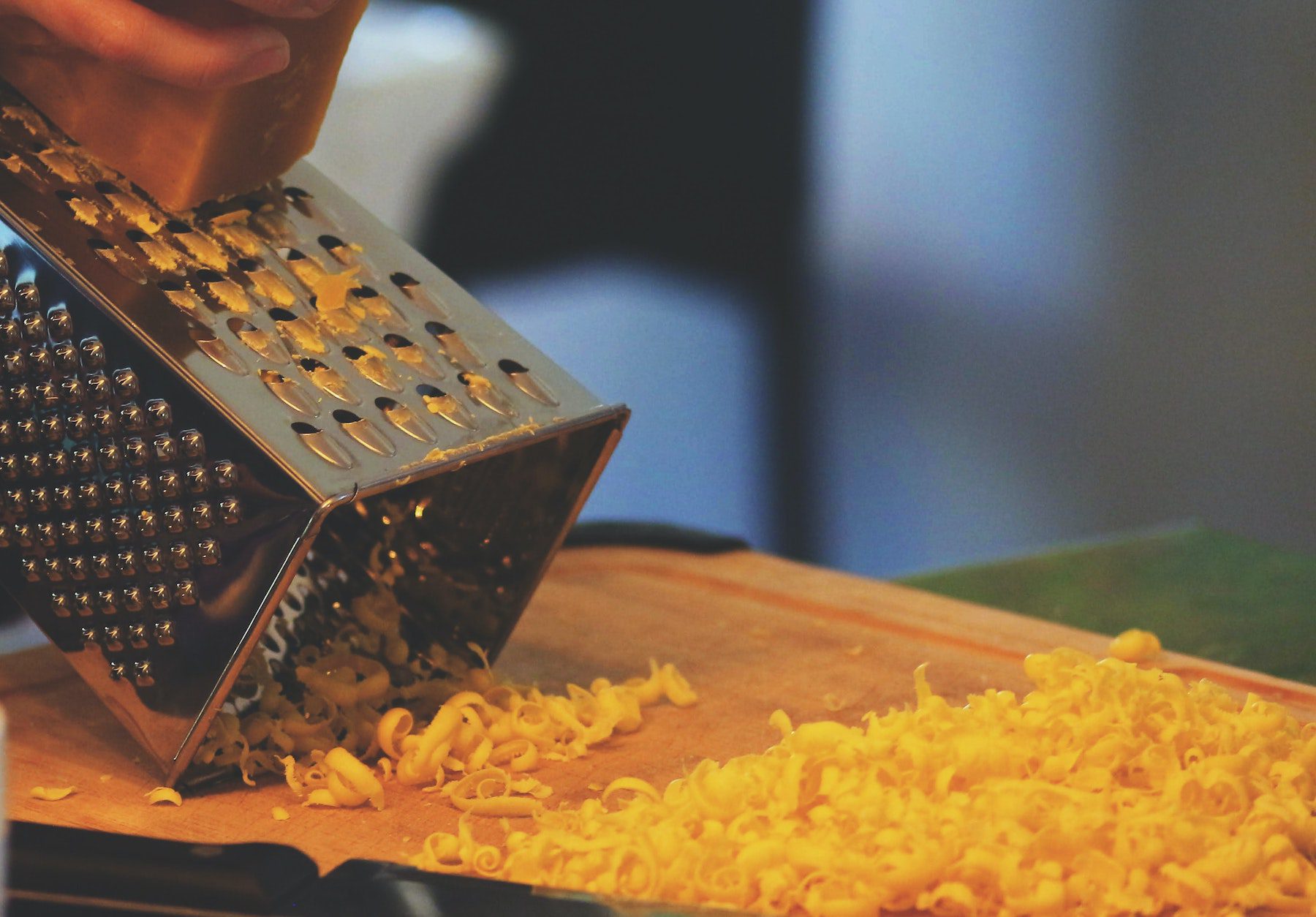 Unseen person grating cheese onto a cutting board. 