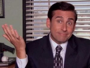 Michael Scott from The Office shrugging to camera in front of his window.