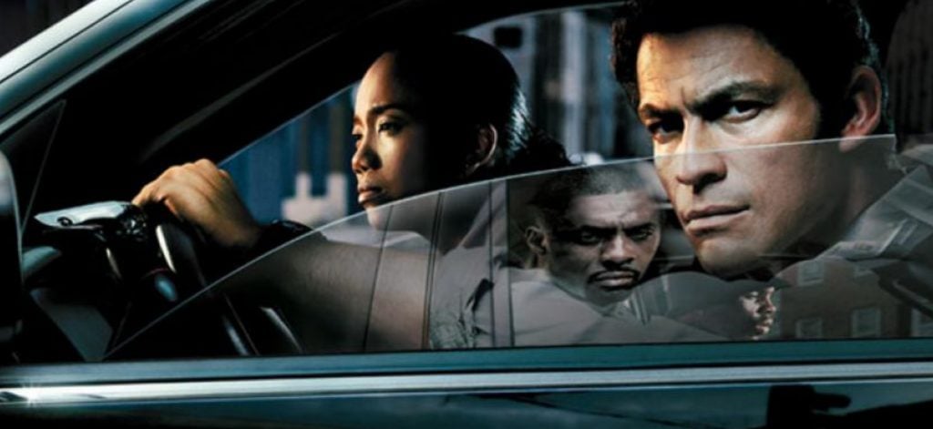 Actors from The Wire staring tensely into distance from front seat of a car.
