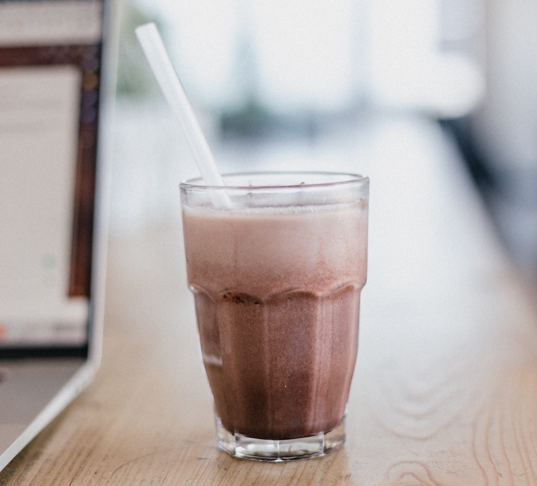 A mocha espresso smoothie in a clear glass with background blurred.