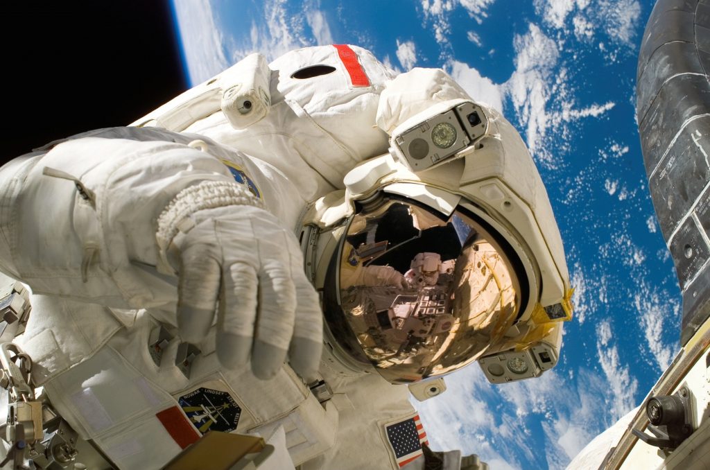 An astronaut suited up floating in outer space with earth in the background.