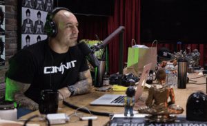 Joe Rogan sitting at desk and microphone recording his podcast.