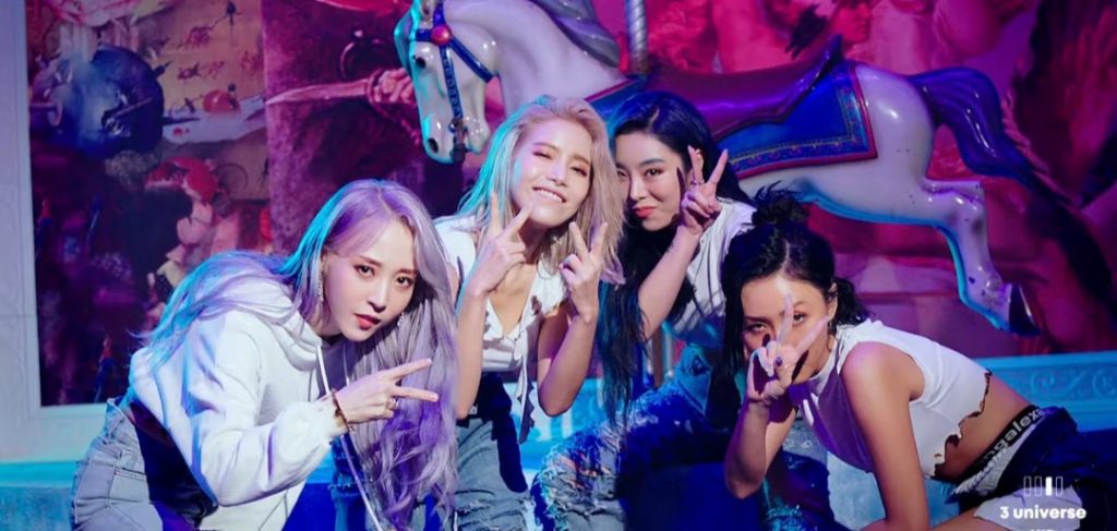 K-pop idol group Mamamoo posing in front of neon illuminated background.