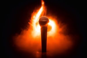 Microphone on fire against dark background with smoke.