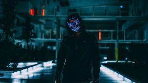 Mysterious figure with neon mask in a scary urban landscape