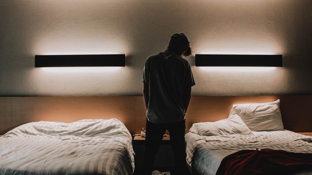 Sleepless man standing between two beds