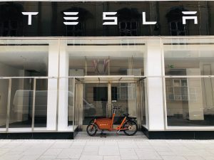 Tesla storefront with a historic antique style vehicle displayed in front