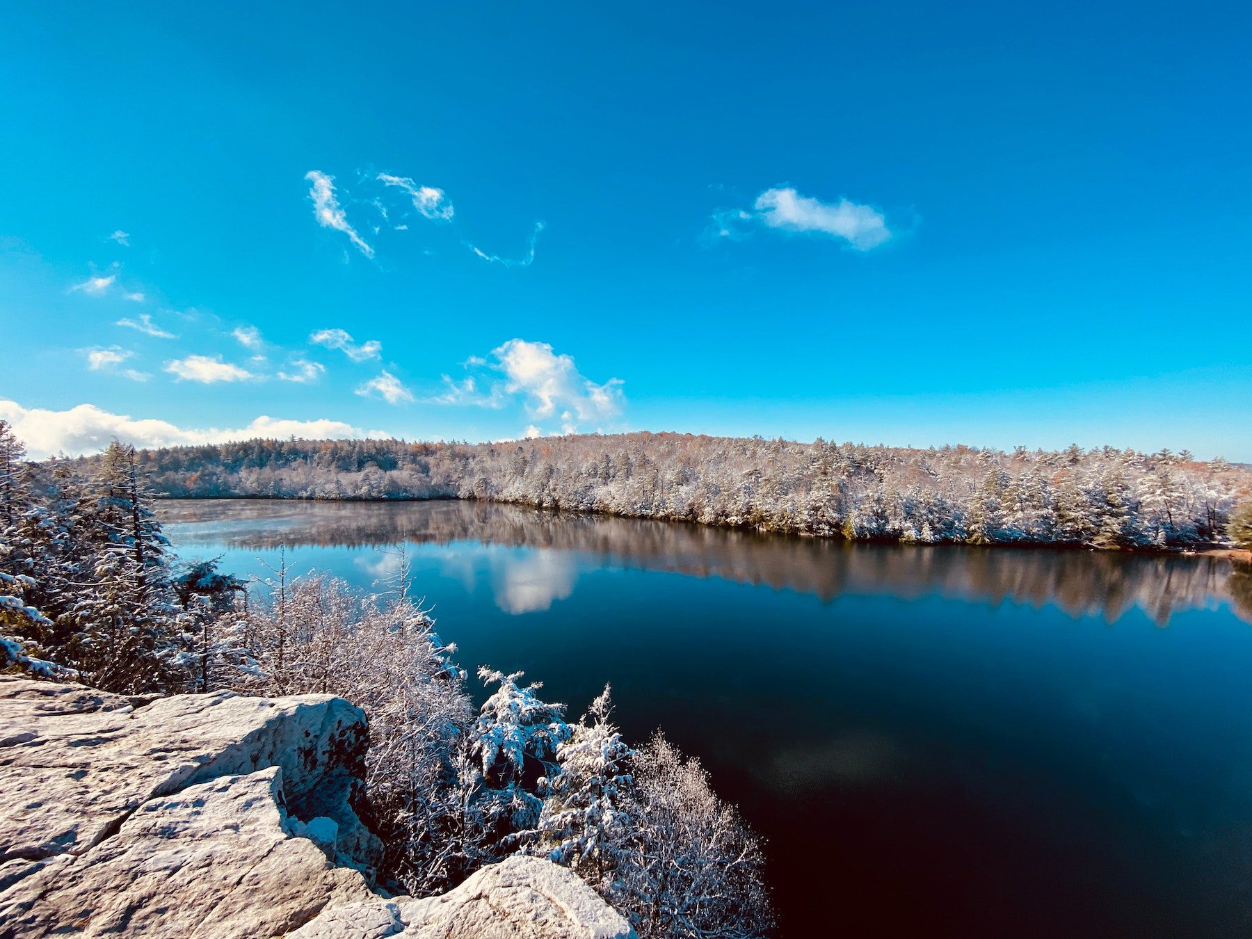 Minnewaska State Park Preserve with a large lake surrounded by snow-flocked trees with a mostly cloudless sky