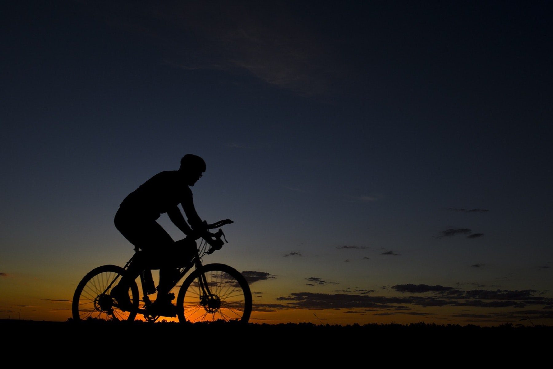 The silhouette of a cyclist on their bike during the sunset. 