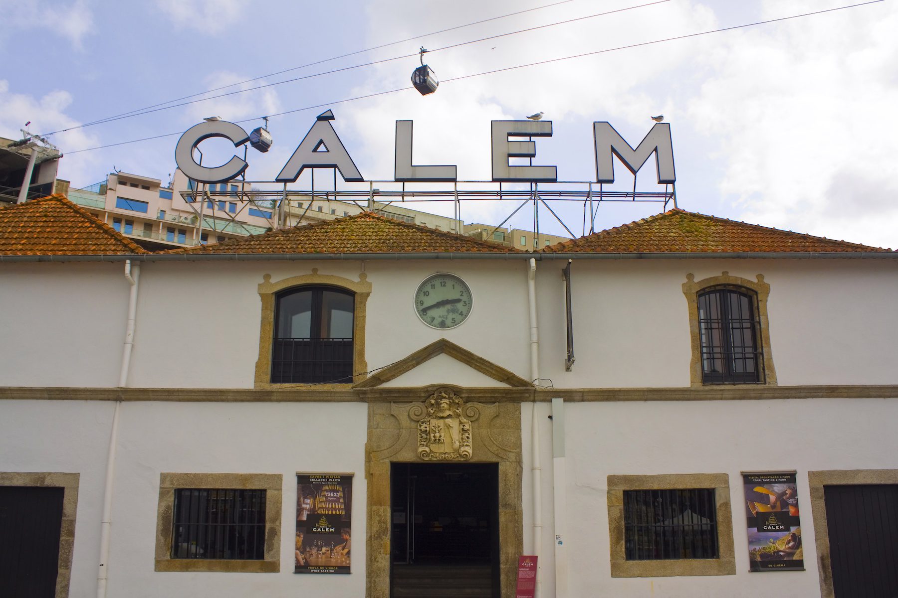 A large sign of "Calem" is displayed atop a white building with a golden brown roof at Calem Winery in Portugal