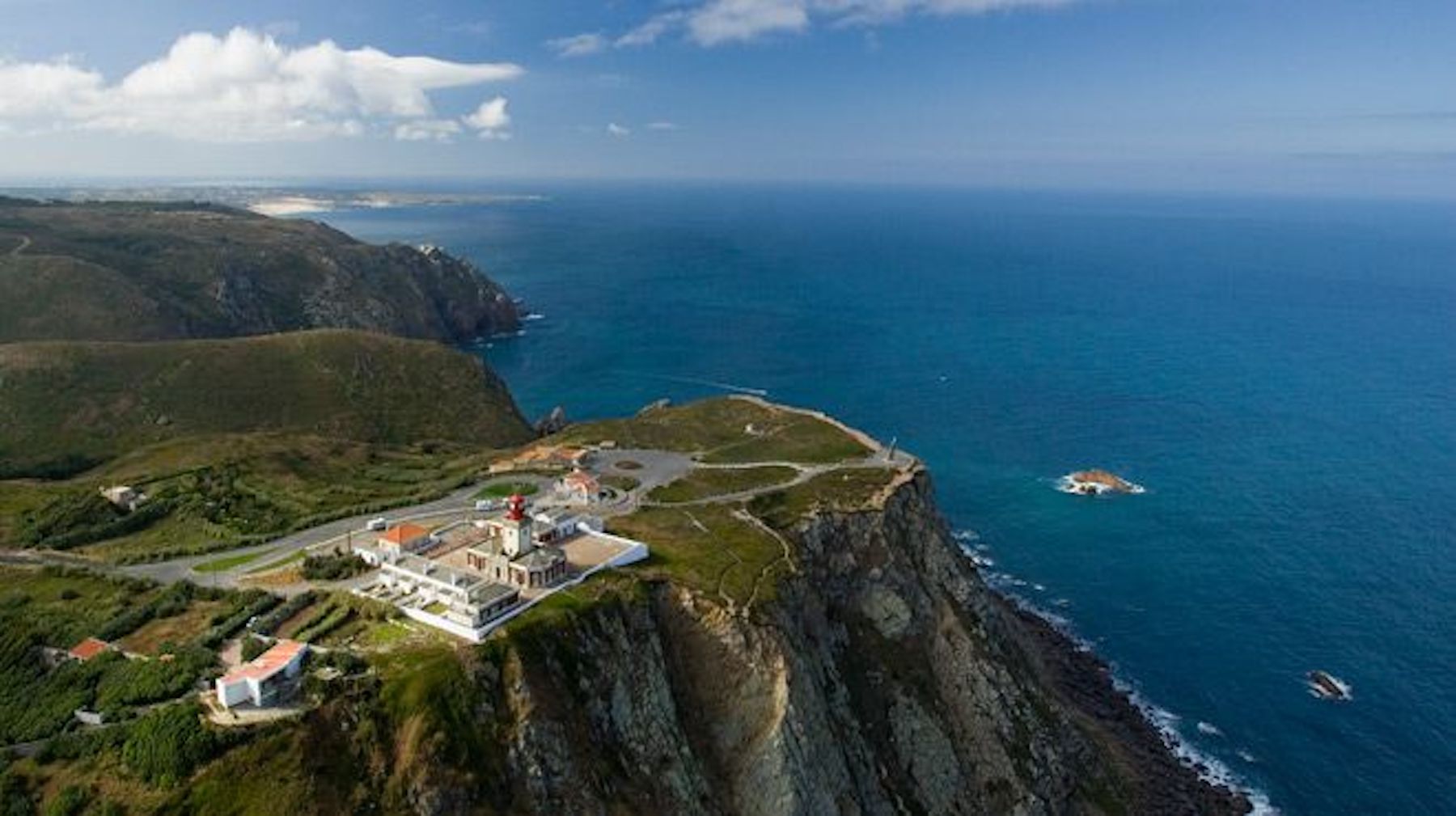 An aerial view of Cabo de Roca, Portugal depicting a large building atop of large cliff overlooking the ocean