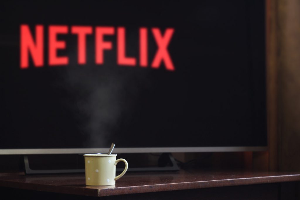 coffee mug in front of a television with the Netflix main screen