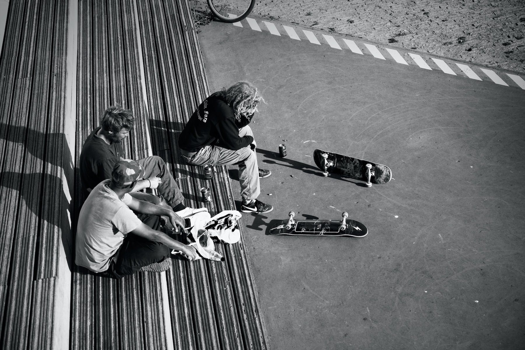A trio of skateboarders taking a break and sipping on soda as they sit upon large steps