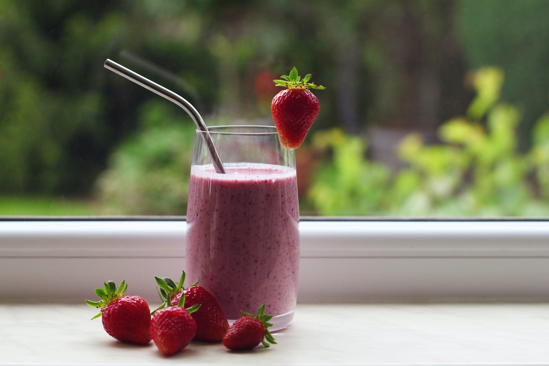 Strawberry smoothie with berries on a windowsill.