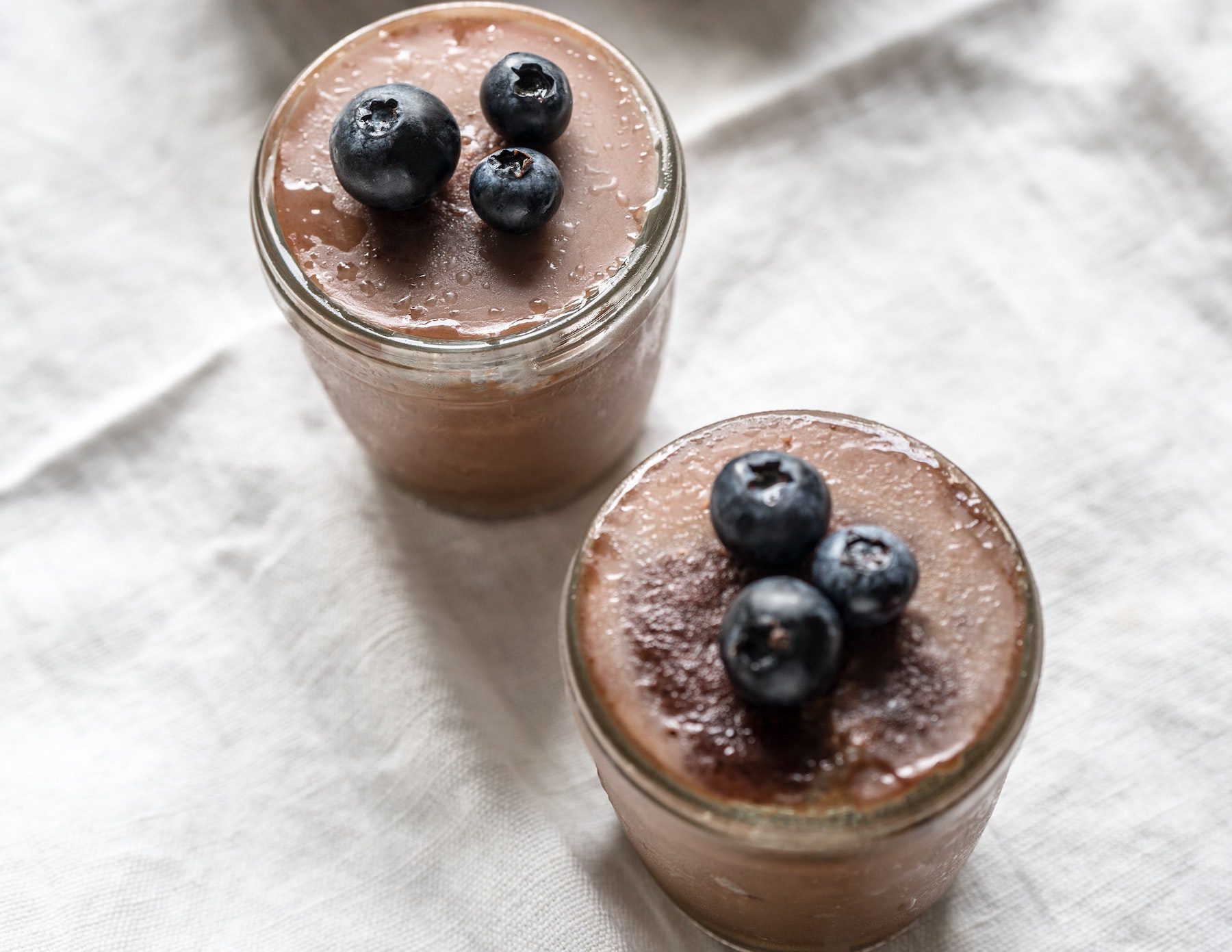 Chocolate blueberry smoothies in mason jars on linen tablecloth.