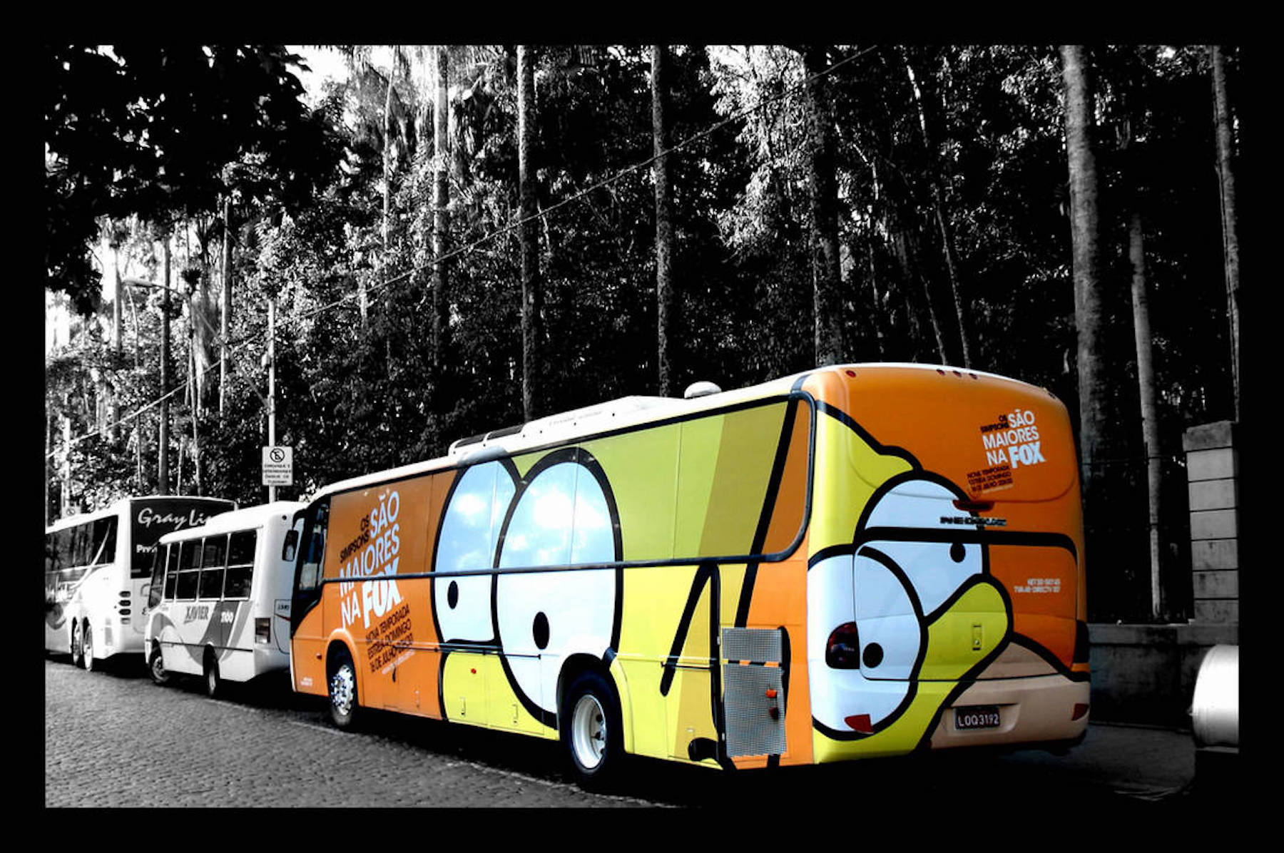 A buss wrapped with artwork of Bart and Homer's eyes against orange background.
