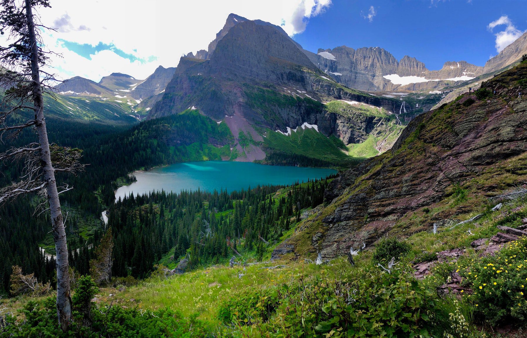 Glacier National Park in United States with stunning view of mountains and crystal blue water with a tree-line shore.