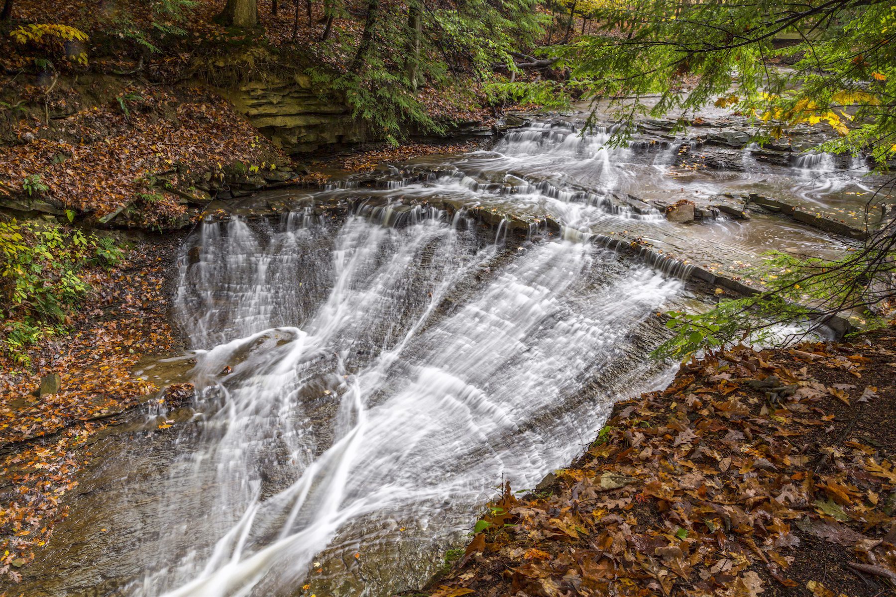 Whitewater cascades over rock ledges of beautiful Bridal Veil Falls, a waterfall photographed in the colorful autumn landscape of Cuyahoga Valley National Park of northeast Ohio.