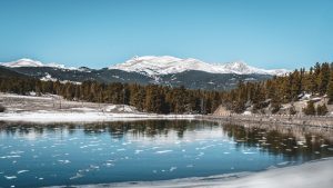 Rocky Mountain, one of America's most popular national parks, during the winter with ice visible in the water and snow on the distance mountaintops.
