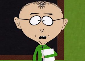 Mr. Mackey holding papers in a classroom.